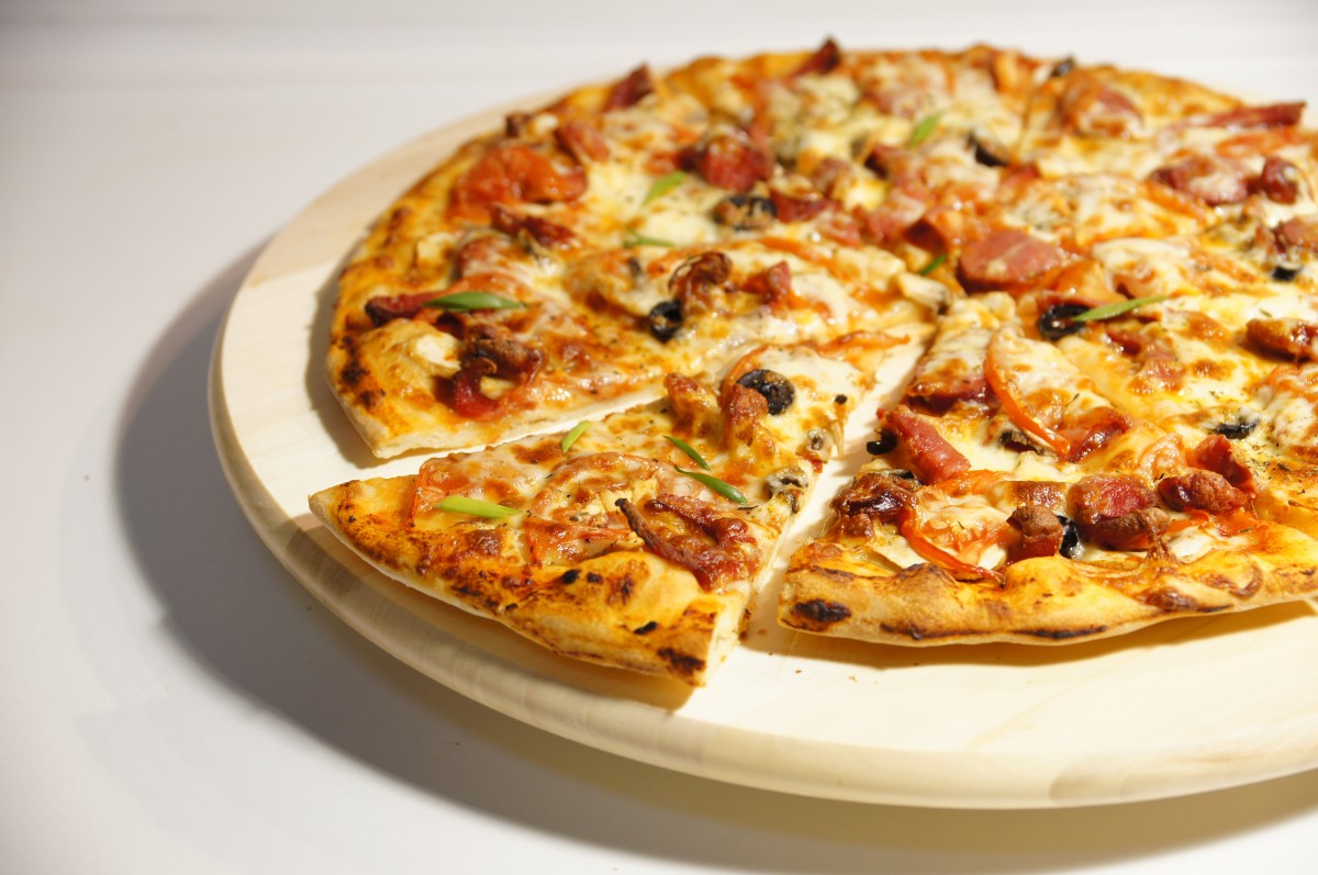 En la imagen se puede ver una pizza sobre bandeja de madera