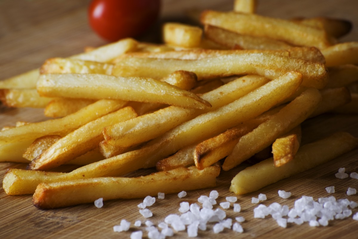 En la imagen se pueden ver patatas fritas sobre una tabla de madera