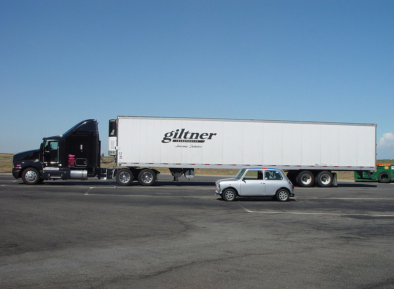 En la imagen se puede ver un gran camión y un coche, representando grande y pequeño
