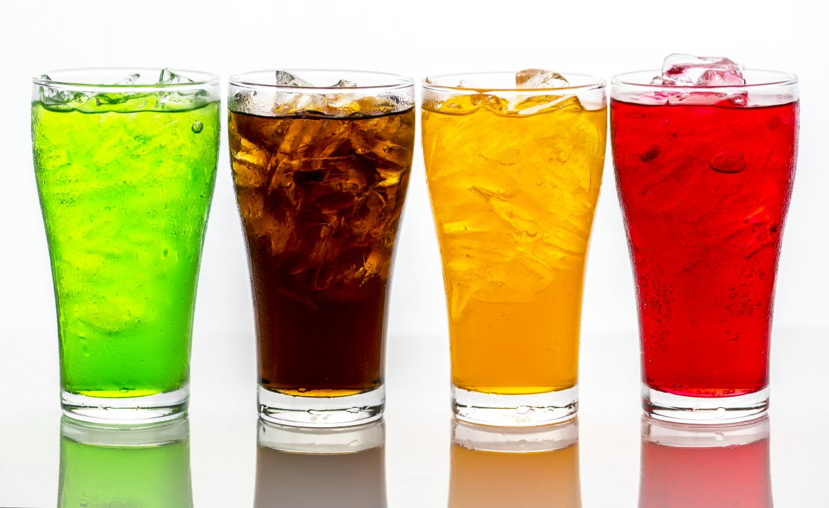 En la imagen puedes ver cuatro vasos con bebidas con gas de distintos colores.