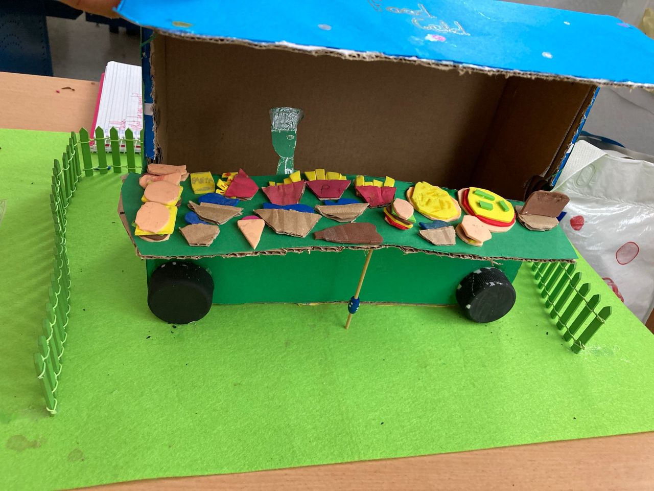 En la imagen se puede ver una camioneta que vende comida hecha con materiales reciclado hecha por niños donde se ven diferentes platos