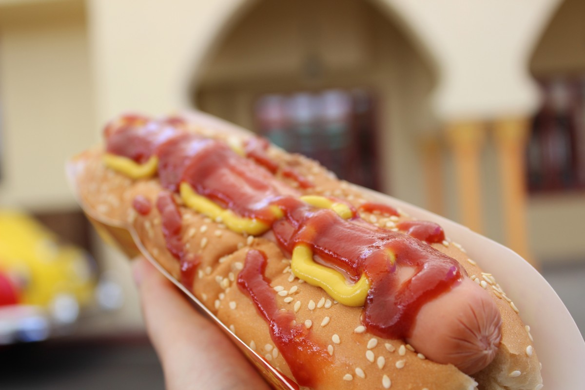 En la imagen puedes ver un hot dog en primer plano con kétchup y mostaza por encima.