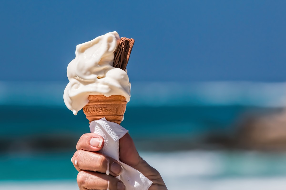 En la imagen se puede ver un helado de vainilla en cucurucho, sujeto por una mano y con una barrita de chocolate dentro