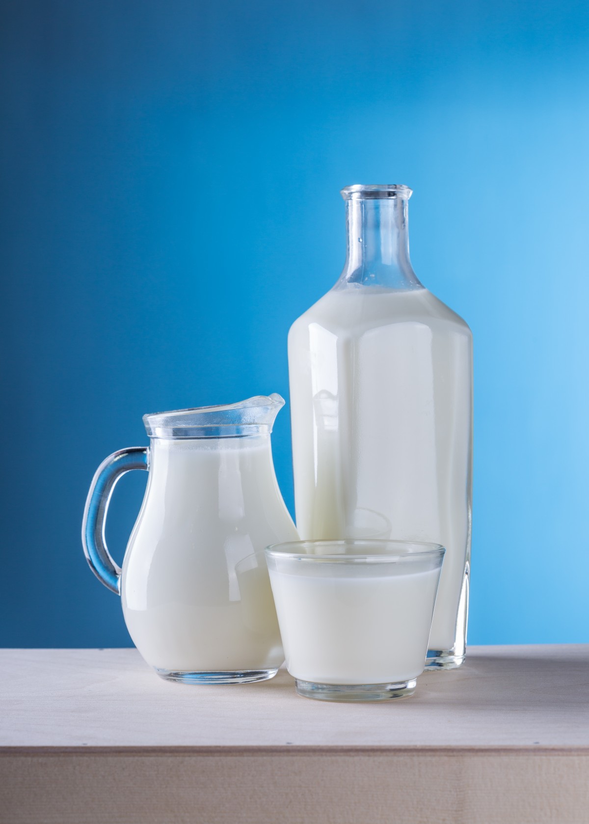 En la imagen se puede ver una botella, una jarra y un vaso de leche