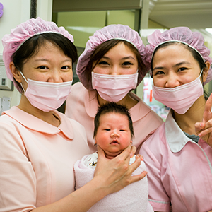 Tres enfermeras posan con un recién nacido