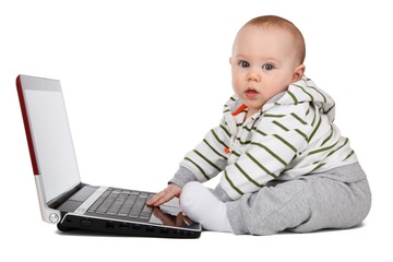 Bebé sentado delante de un ordenador portátil mirando a cámara.