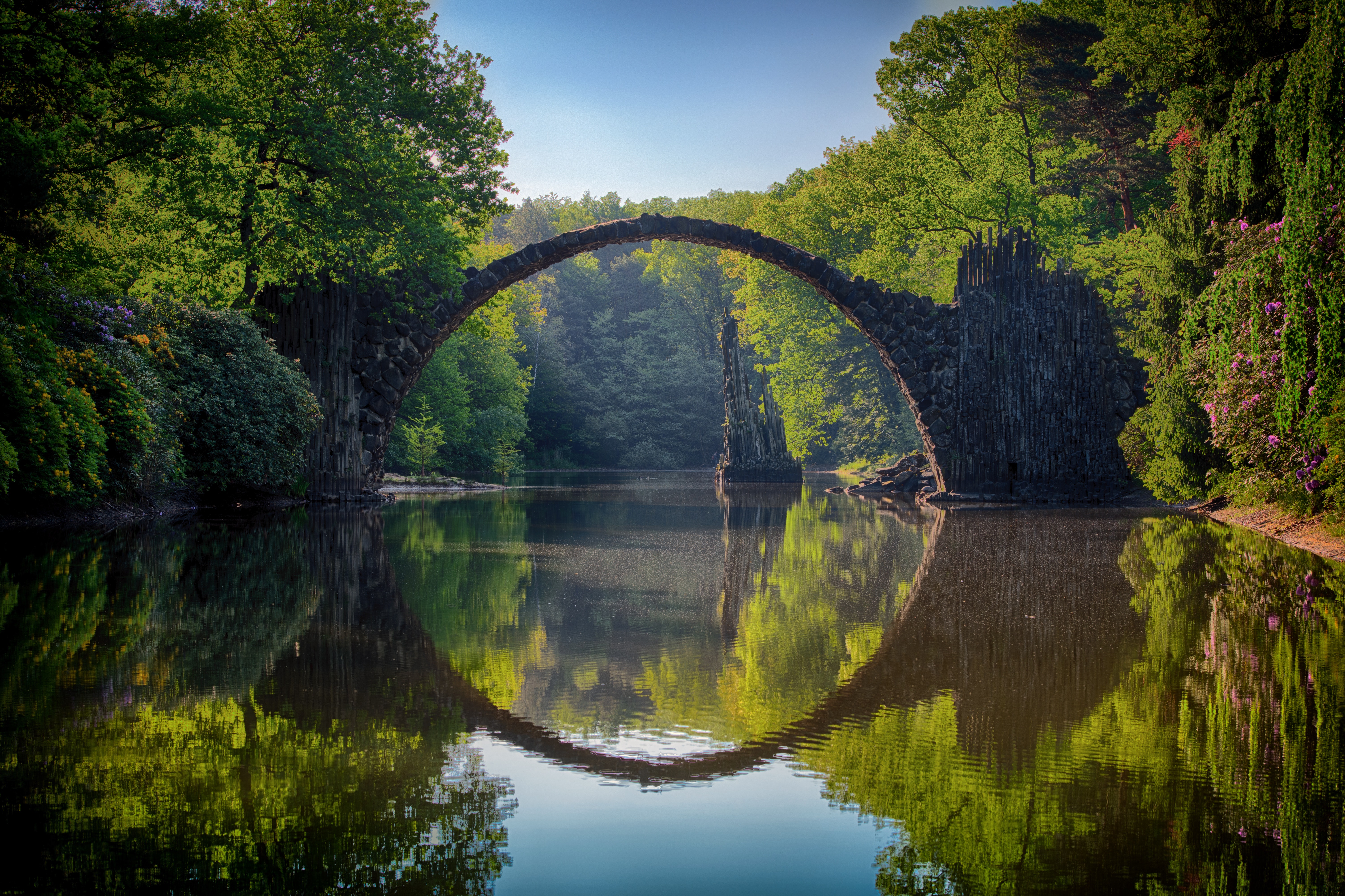 La imagen muestra el puente de Rakotzbrücke y su reflejo en el agua formando una circunferencia