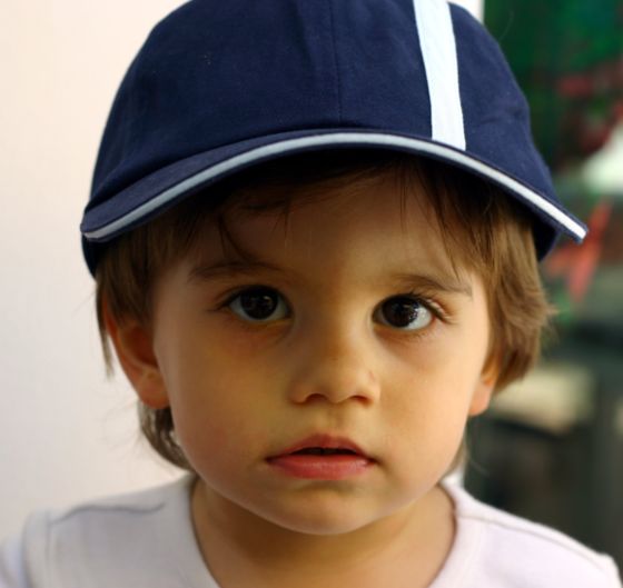 En la fotografía aparece un niño con una gorra puesta de color azul marino y un filo blanco.
