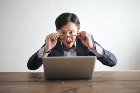 En la fotografía aparece un señor oriental con unas gafas puestas, está mirando el ordenador. La expresión de la cara es de sorprendido de lo que ve por el ordenador.