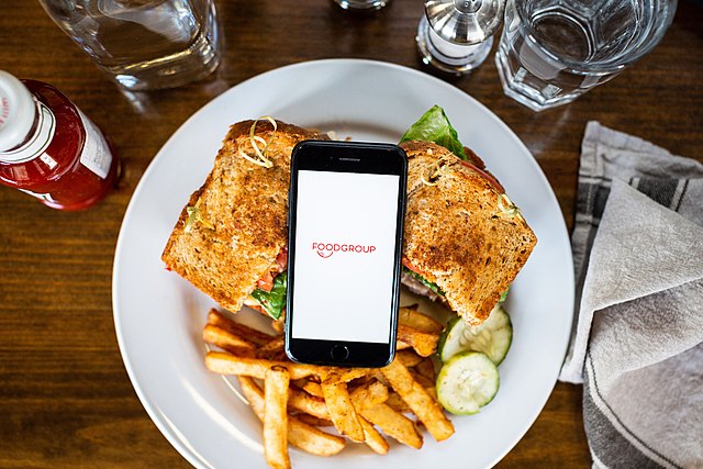 La imagen muestra un móvil sobre un plato de comida