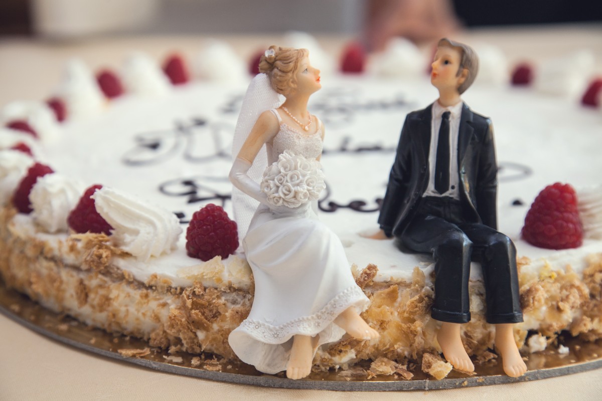 La imagen muestra unos muñecos de boda encima de una tarta