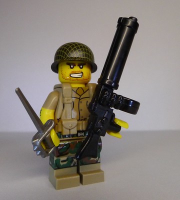 La imagen muestra un muñeco hecho con pequeñas piezas de colores que representa a un soldado de guerra con una espada y una metralleta.