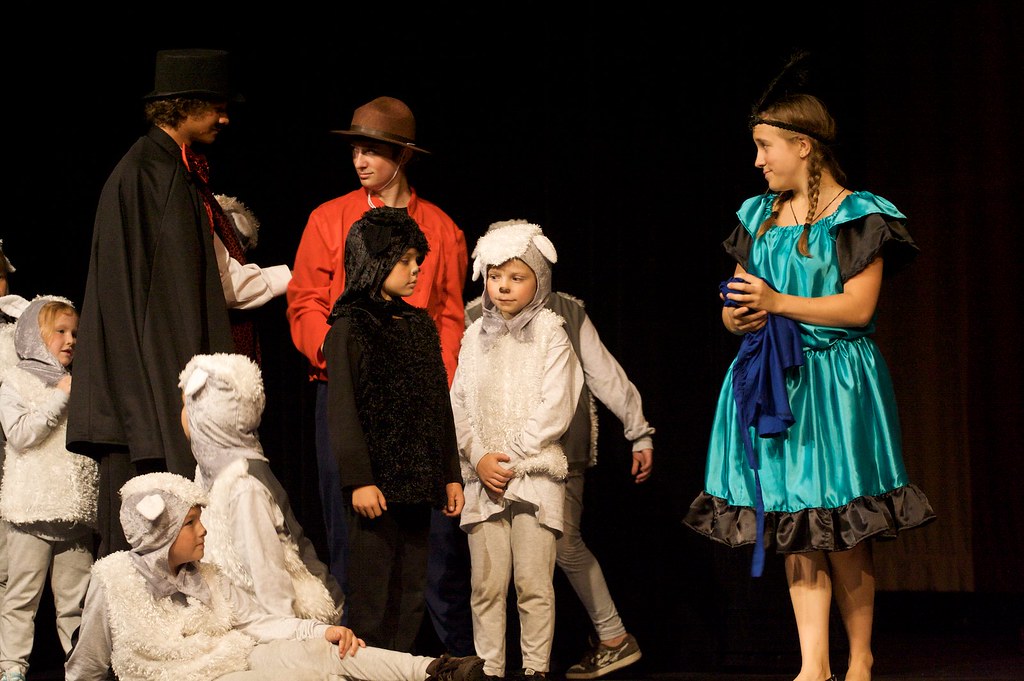 La imagen muestra a un grupo de estudiantes en el escenario haciendo un teatro.