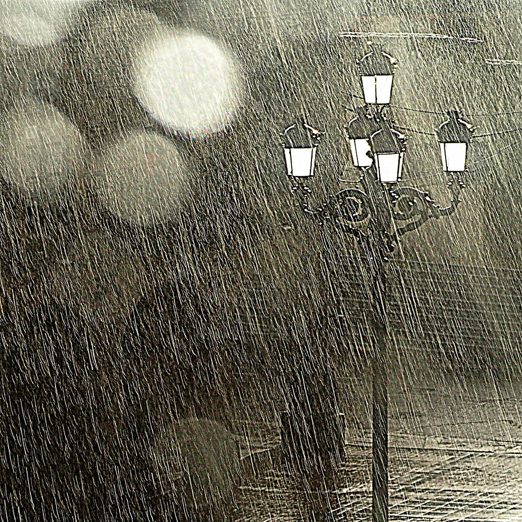 La imagen muestra una farola en la oscuridad en un día de lluvia intensa.