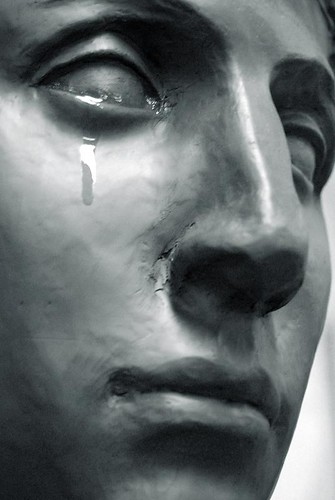 La imagen muestra la cara de una estatua con una lágrima que cae en su rostro.