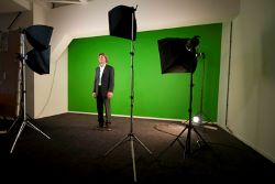  Fotografía de una pared de color verde con un hombre delante y unos focos iluminando la escena.  