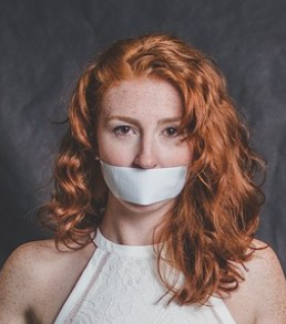 Mujer que tiene la boca tapada para representar el no poder hablar de algún tema por ciertos respetos, prejuicios sociales u otras razones.