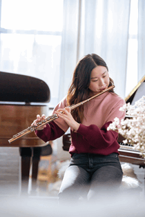 La imagen muestra a una chica japonesa tocando la flauta. Ella está ensayando para tocar en un concierto