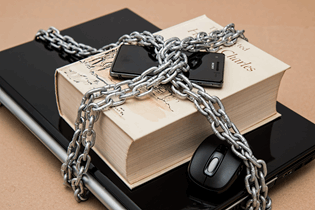  La imagen muestra un ordenador portátil, un libro y un teléfono móvil sujetados por una doble cadena.