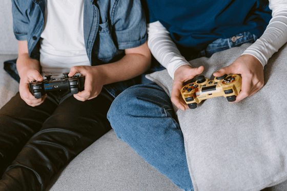 La imagen muestra las manos de dos niños sujetando cada uno un mando de consola de videojuegos.
