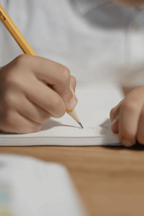 La imagen muestra una mano escribiendo sobre un papel.