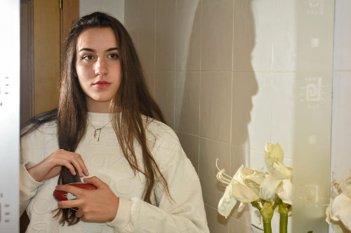  La foto muestra una chica delante de un espejo peinándose.