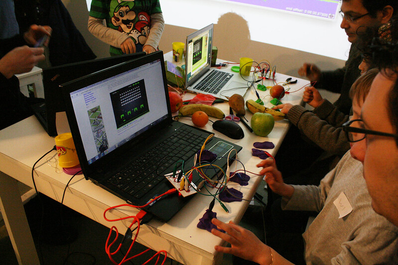 Se muestran varias personas manipulando instrumentos hechos con Makey Makey y Scratch