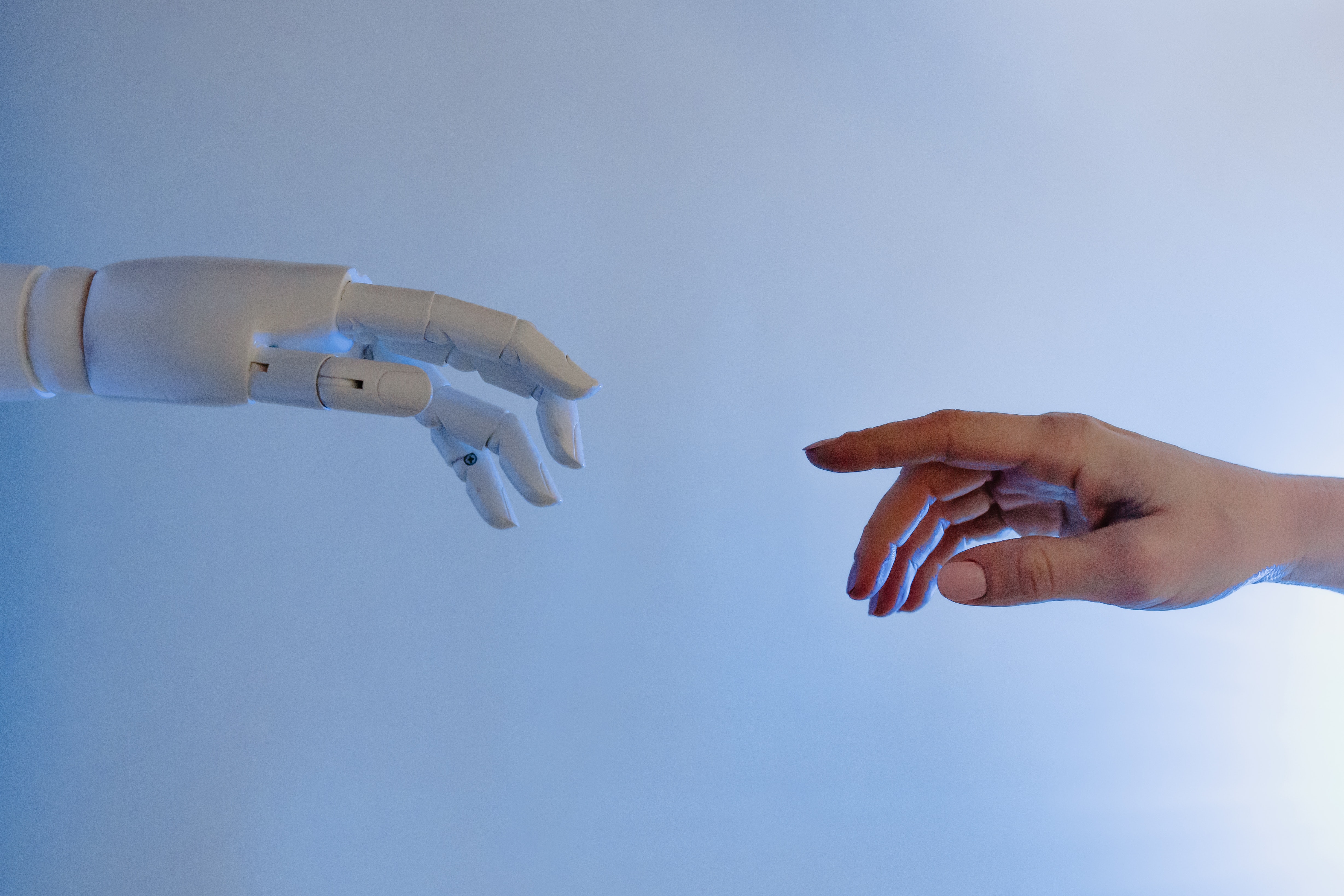 Dos manos, una robótica a la izquierda y otra humana a la derecha intentando tocarse