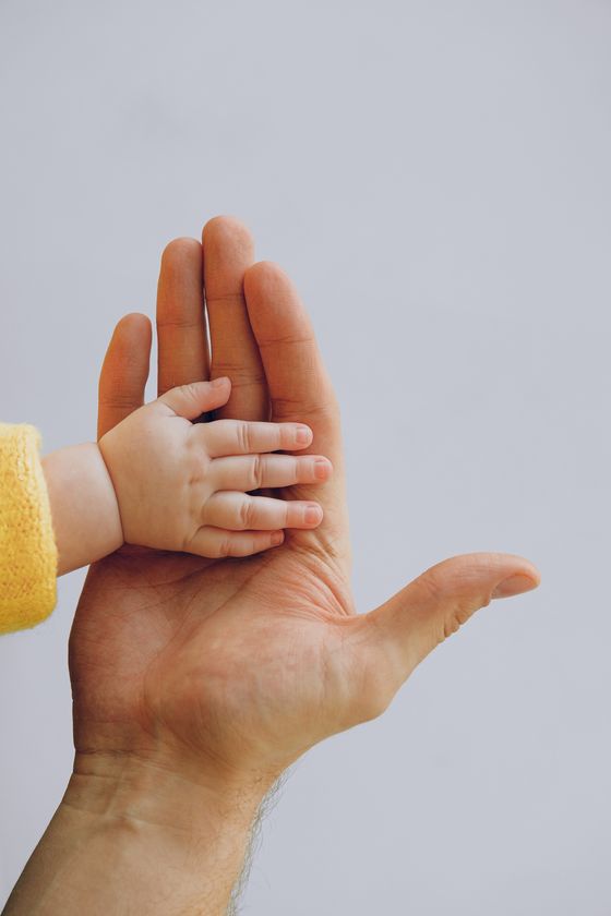 Mano de un bebé sobre la mano de un adulto.