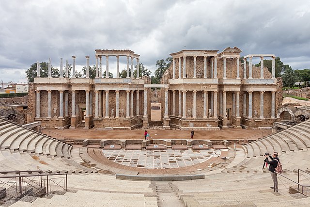 Fotografía del Teatro Romano de Mérida desde la parte superior de las gradas. Se aprecia el escenario y las columnas que quedan de pie. 