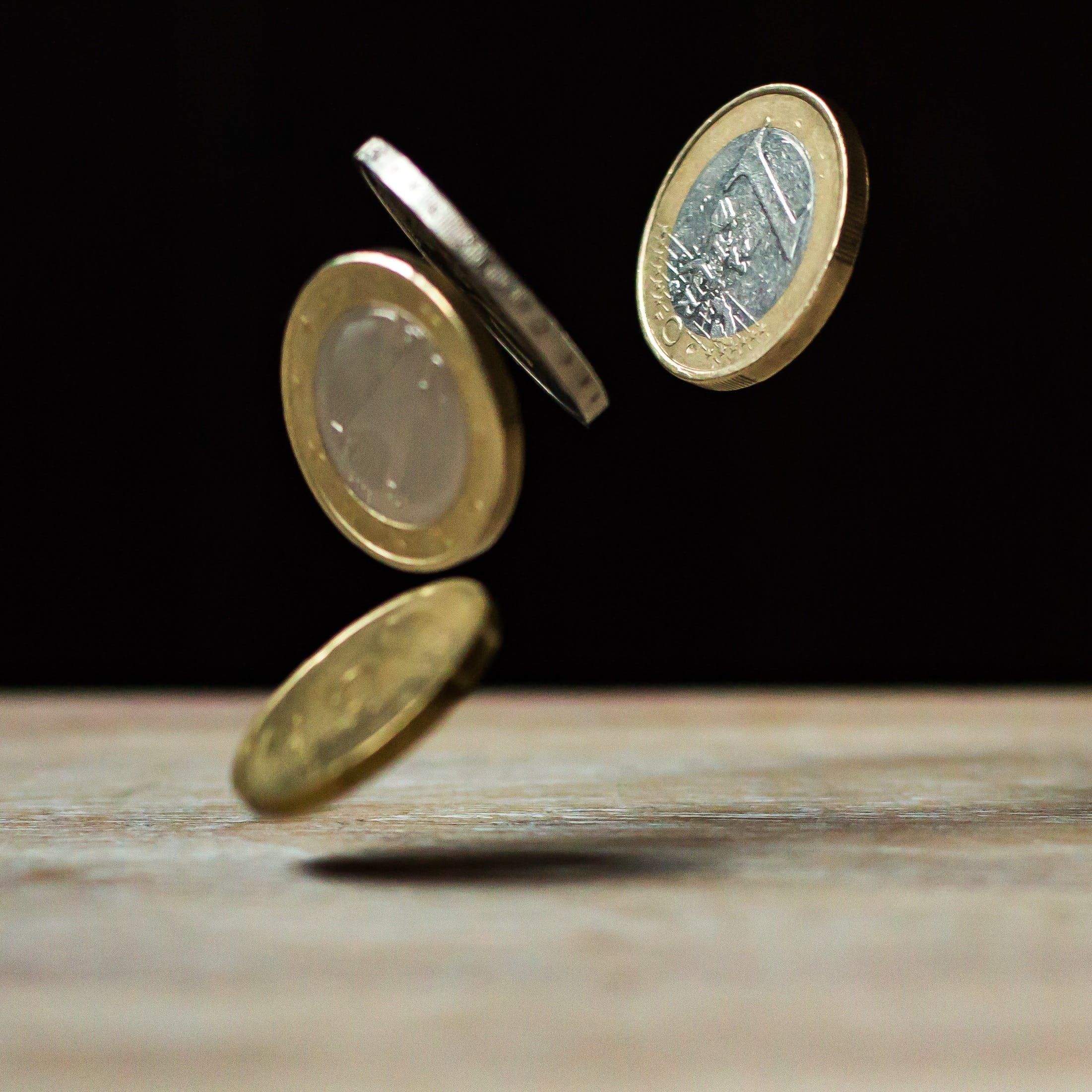 La imagen muestra cuatro monedas de un euro en el aire. 
