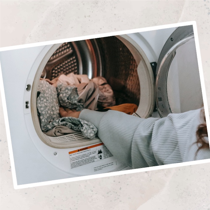 La imagen muestra un brazo metiendo ropa en una lavadora