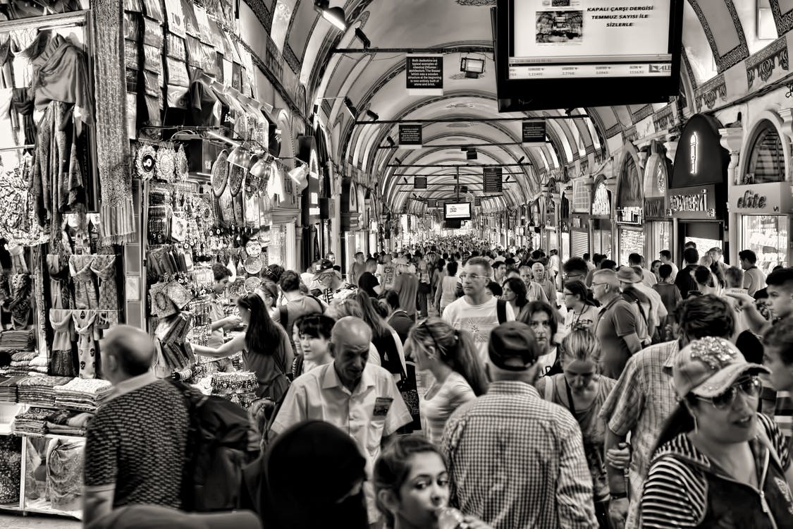 La imagen muestra un mercado en la calle lleno de gente y de puestos con productos típicos del lugar, 
