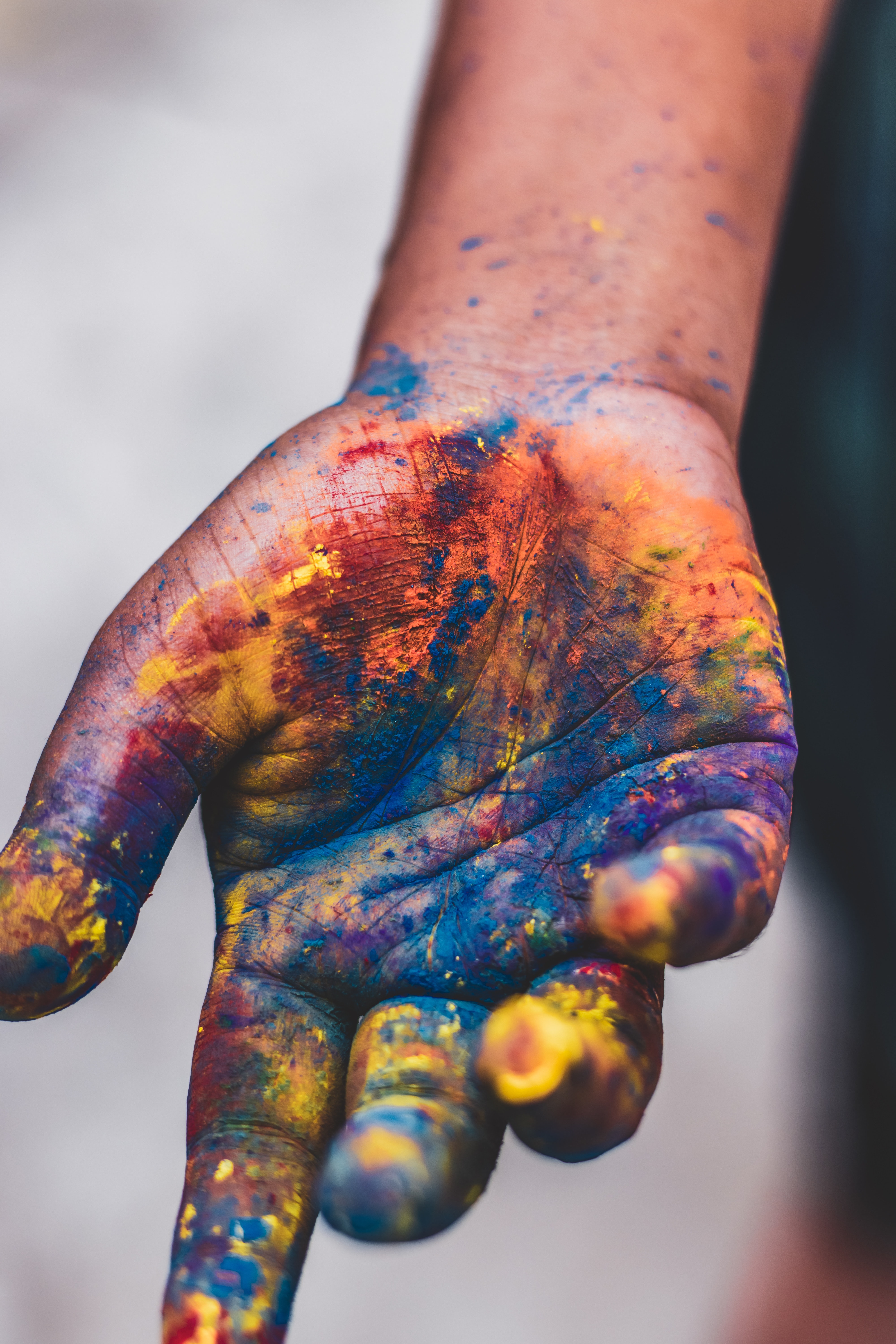 La imagen muestra una mano sucia de pinturas de colores. 