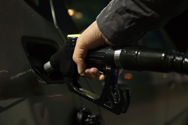La imagen muestra el brazo de una persona sujetando una manguera de combustible que introduce en su vehículo.
