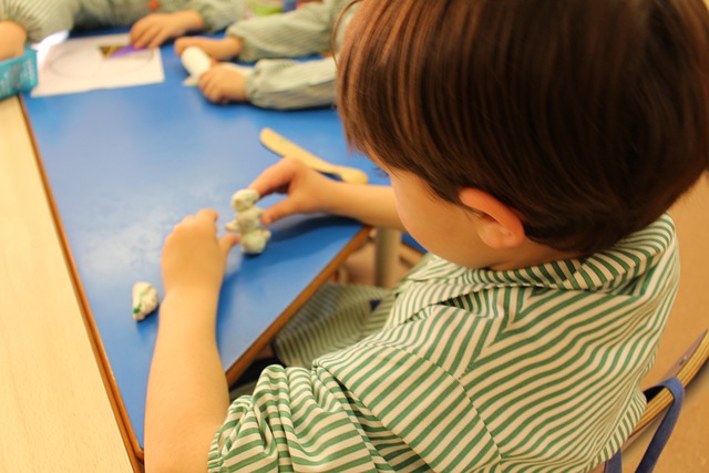 Un niño de infantil juega con plastilina