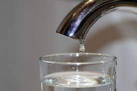 Imagen que muestra un grifo del que cae una gota de agua en un vaso.