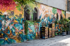 La imagen muestra un muro pintado con edificios, árboles y otras figuras abstractas de muchos colores.