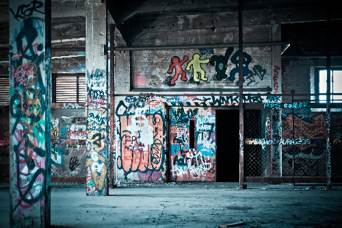La imagen muestra un callejón abandonado con muchas pintadas en las paredes.
