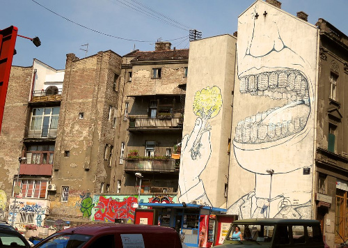La imagen muestra una boca gigante que tiene edificios en lugar de dientes y se está comiendo un árbol.