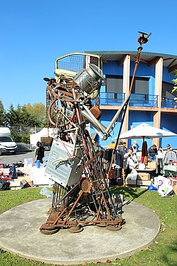 La imagen muestra un montón de chatarra de hierro oxidado queriendo hacer una gran escultura en un parque que podría parecer un caballero armado con una lanza.