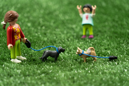 La imagen muestra una representación hecha con figuritas de un perro que ha escapado de su dueño y corre hacia otro perro.