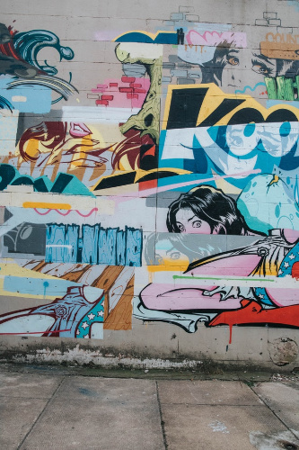  La imagen muestra trozos de distintos graffitis sobre una pared en la calle.