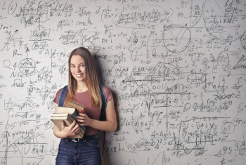 La imagen muestra una chica delante de un panel de fórmulas matemáticas