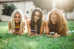 La imagen muestra adolescentes con sus móviles