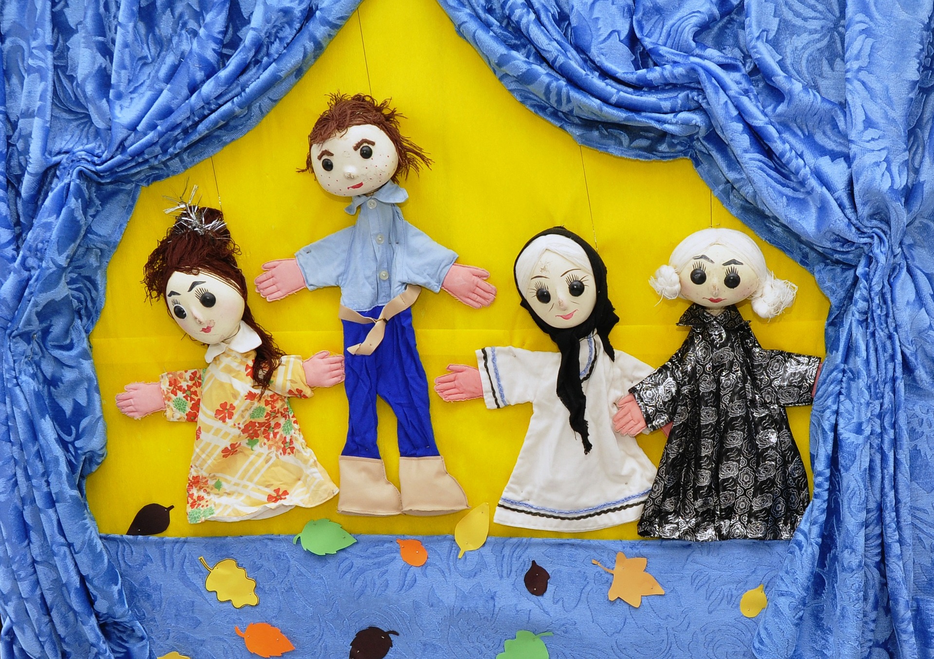 Cuatro marionetas diferentes en un guiñol con telón azul y fondo amarillo.