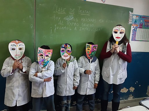 Un grupo de alumnos con su maestra probando las máscaras que han hecho en el aula de teatro
