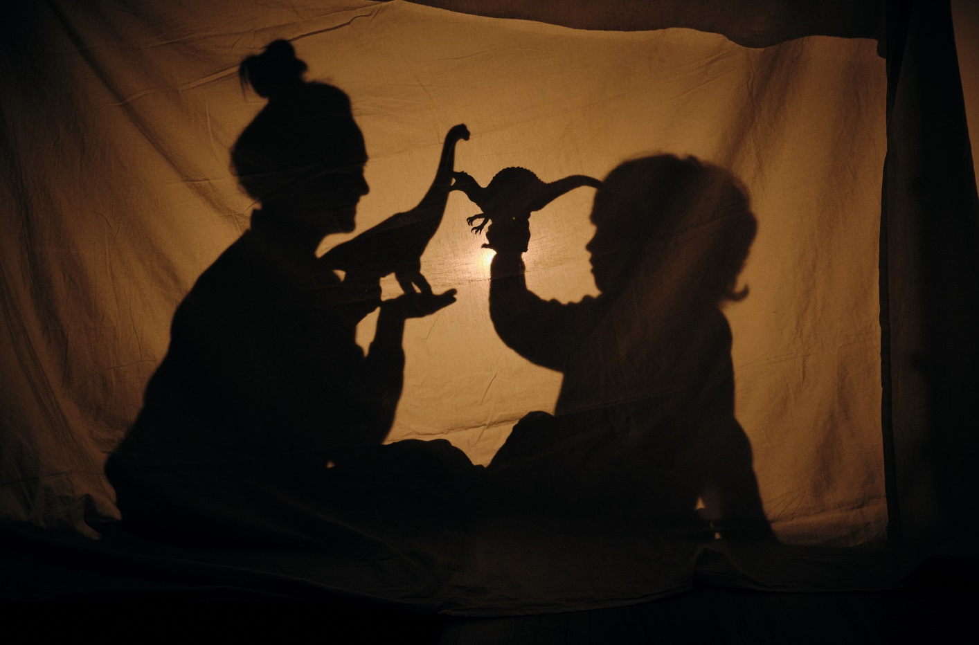 Teatro de sombras en el que aparecen las siluetas de una mujer y un niño.
