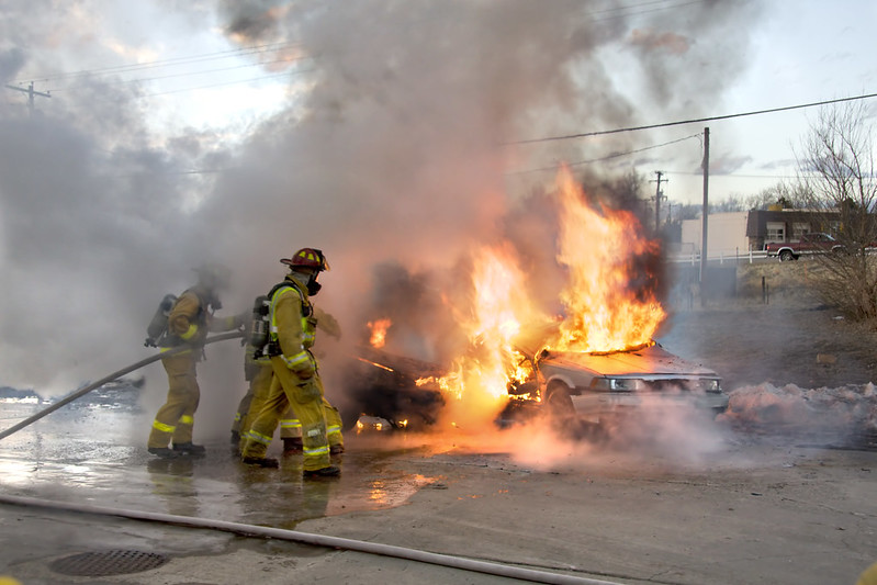 En la imagen puedes ver un grupo de bomberos trata de apagar un coche en llamas