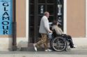 Hombre empujando a otro hombre que va en silla de ruedas.